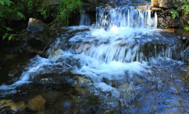 Miniature waterfalls of a small rocky river in the forest