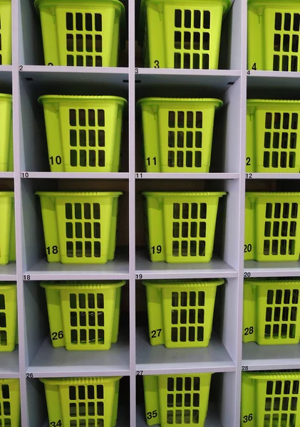 Green boxes for personal belongings on a shelves of wooden bookcase for vertical story