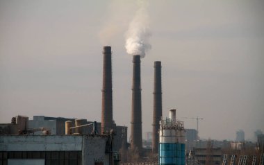 Clouds of smoke from the smokestacks of an industrial plant pollutes the air in a suburban area