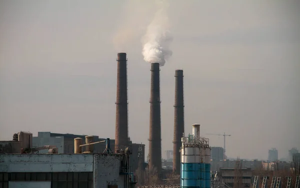 Clouds of smoke from the smokestacks of an industrial plant pollutes the air in a suburban area