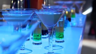 Aydınlatılmış bar tezgahında farklı odak video görüntüleri olan çeşitli kokteyller.