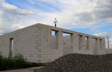 Tamamlanmamış bir evin önünde kum ve çakıl yığınları olan bir kır evi inşaatı.