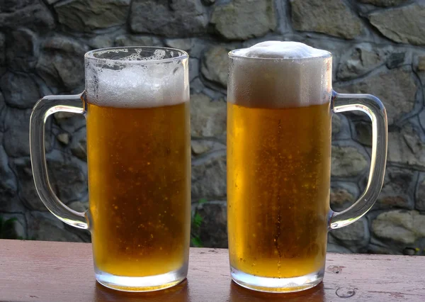 Dwa Kieliszki Zimnego Piwa Bujną Pianką Drewnianym Biurku Kamiennym Tłem — Zdjęcie stockowe