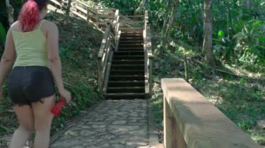 Joven mujer subbiendo escaleras con arboles al refordor