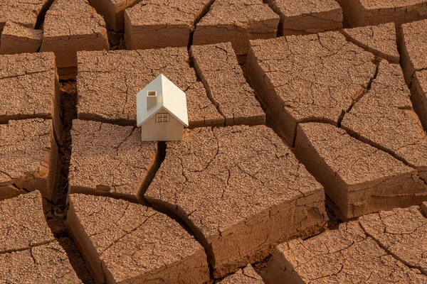 沙漠中裂开的红土上矗立着一座木制的象征性房屋 — 图库照片