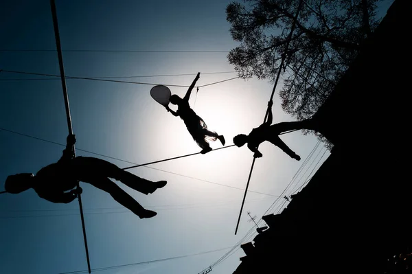 Silhouettes of street tightrope walkers performing