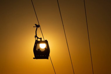 Bir yaz akşamı, havadan teleferik yolunun kenarındaki kulübedeki insanların siluetleri.