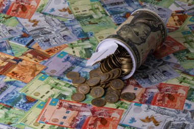 Üzerinde 10 dolarlık banknot, 100 Kazakistan parası ve Kazakistan kağıt parasının resmi olan açık bir kumbara.
