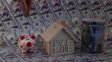 Bir adamın eli Amerikan sikkelerini üç farklı kumbara içine indirir. 100 Amerikan doları banknotlarının arka planına karşı.