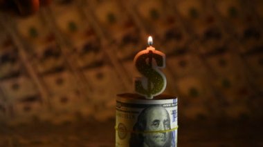 100 dolarlık banknotların arka planında Amerikan doları şeklinde yanan bir mum.