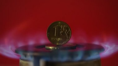 Bozuk para 1 Rus rublesi sıcak bir gaz ocağında duruyor.