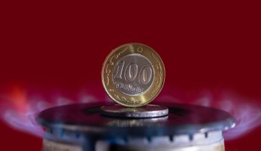 Yanan bir gaz ocağına 100 Kazak tenge madeni para