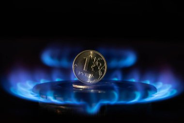 Bozuk para 1 Rus rublesi sıcak bir gaz ocağında duruyor.