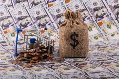 Arkaplanda Amerikan dolarının sembolü olan düğüm torbası 100 Amerikan doları değerinde banknotlar.