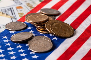 Amerikan bayrağının arka planında 1 ABD doları ve 25 sentlik madeni paralar