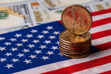 Amerikan bayrağının arka planında 1 ABD doları ve 25 sentlik madeni paralar