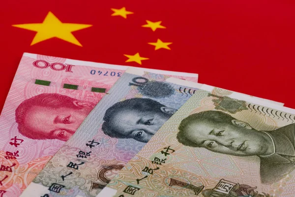 Çin bayrağının arka planına karşılık 1, 10 ve 100 Yuan 'lık banknotlar.