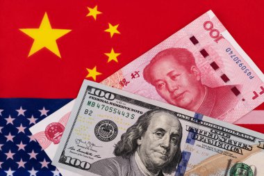 Ulusal bayrakların arka planına karşı 100 Amerikan doları ve 100 Çin yuanı banknotları