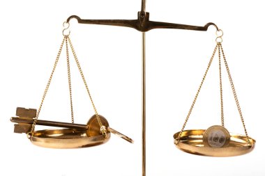 Terazinin bir tarafında 100 Kazakistan tonu ve terazinin diğer tarafında da altın bir anahtar var.