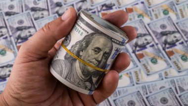 Rolled up stack of 100 dollar bills in a man's hand