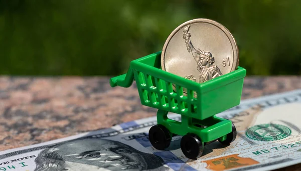 1 dollar coin in a miniature shopping cart