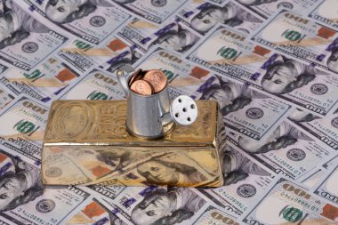Büyük bir altın külçesi, 1 sentlik bozuk para ve 100 dolarlık banknotlarla dolu minyatür bir sulama kutusu.