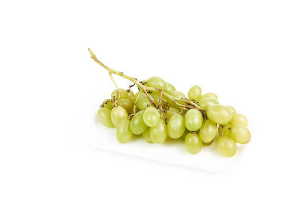 Кластер зеленого винограда на белом подносе на белом фоне. Концепция здорового и вегетарианского питания