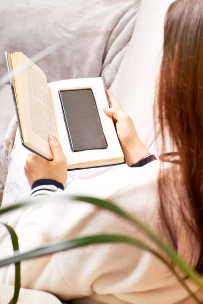 Young Woman Reading Book Mobile Phone Embedded Its Pages Vertical — Stock Photo, Image