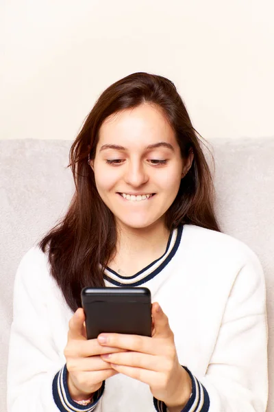 Happy millennial generation Hispanic Latina woman looking at cell phone screen, feeling excited reading a message, internet success