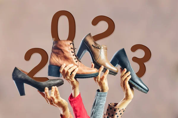 Hands holding different womens shoes and boots with year 2023 on them. New year concept. Party