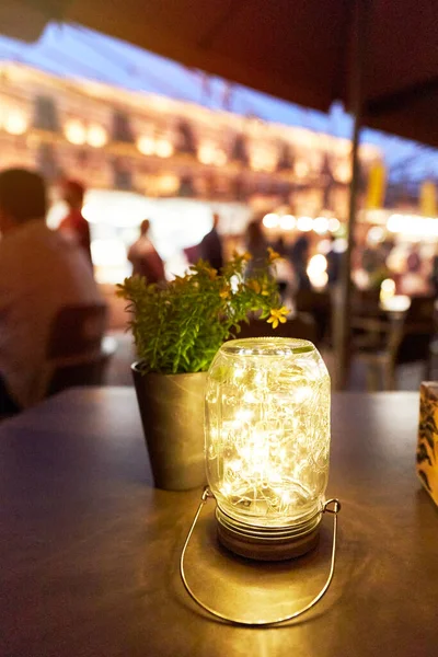view of a wooden table on the terrace of a bar at night. Led lamp on a table