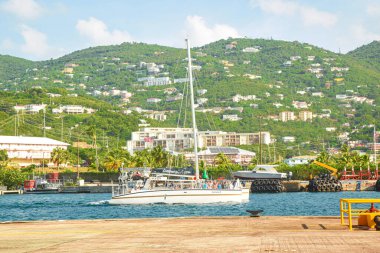 Katamarlı bir tekne dolusu yolcu şehrin arka planından 124 no 'lu gemiyle denize açılıyor turistler Virgin Adası' ndaki küçük bir ada olan St Thomas 'ta, körfezdeki Katamaran teknesinde tura çıkıyorlar. 