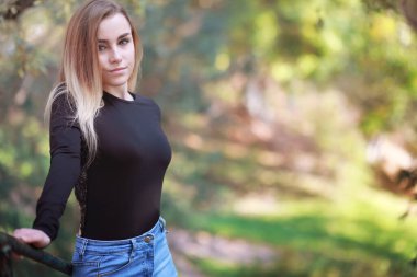 Sonbahar parkında yürüyüş yapan genç ve güzel bir kız. Şehir parkında yapraklar dökülüyor. Ekim.