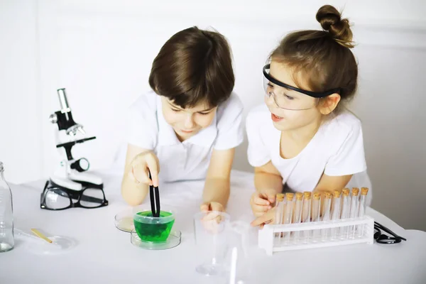 Two cute children at chemistry lesson making experiments isolated on white backgroun