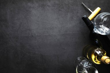 Masada bir bardak kırmızı şarap. Siyah şişe ve bir bardak şarap..