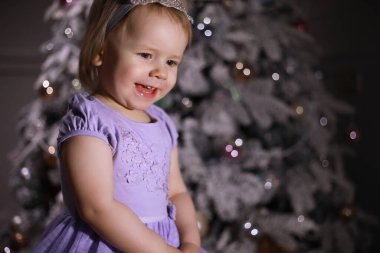 Noel ağacının önünde şık giyinmiş bir çocuk. Yeni yılı bekliyorum..