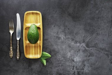 Avokado yemek tarifleri. Tahta kesme tahtasında servis edilen olgun yeşil avokado..