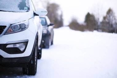 Modern SUV arabası kış yolunun kenarında duruyor. Kayak merkezine aile gezisi. Kış ya da bahar tatili macerası. Araba kışın karlı yolda dağlarda