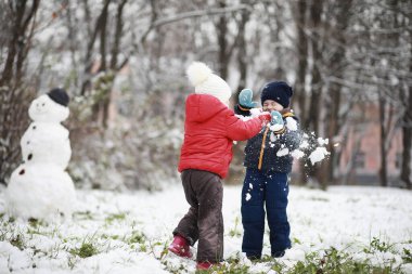Kışın parktaki çocuklar sno ile oynarlar.