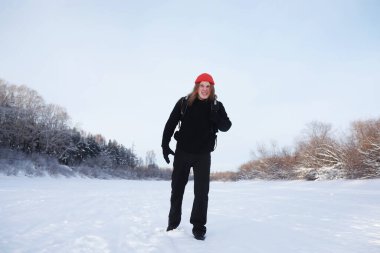 Bir adam sırt çantasıyla seyahat eder. Ormanda kış yürüyüşü. Kışın parkta yürüyüş yapan bir turist..