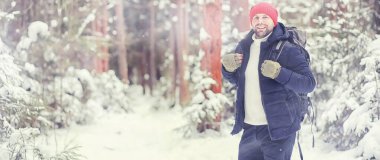 Bir adam sırt çantasıyla seyahat eder. Ormanda kış yürüyüşü. Kışın parkta yürüyüş yapan bir turist..