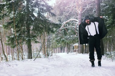 Kış ormanlarında sakallı adam. Çekici, mutlu, sakallı genç bir adam parkta yürüyor..