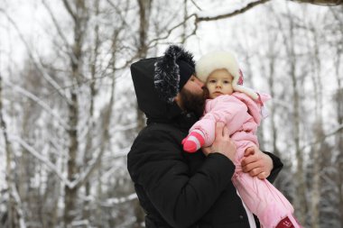 Mutlu bir aile kışın dışarıda karda oynar ve güler. Şehir parkı kış günü.