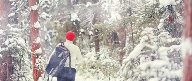 Bir adam sırt çantasıyla seyahat eder. Ormanda kış yürüyüşü. Kışın parkta yürüyüş yapan bir turist..