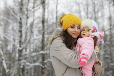 Mutlu bir aile kışın dışarıda karda oynar ve güler. Şehir parkı kış günü.