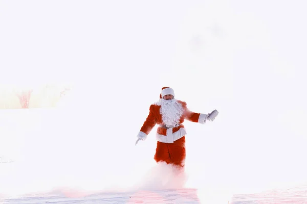 冬のフィールドでサンタ サンタ魔法の霧のフィールドに沿って歩いてください クリスマス イブのサンタは赤いバーで子供たちにプレゼントを運んでいる — ストック写真