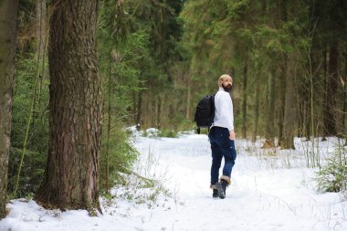 Palto ve İskoç kumaşlı yakışıklı bir adamın açık hava portresi. Kış ormanlarında sakallı adam.