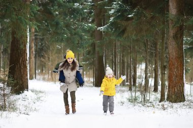 Mutlu bir aile kışın dışarıda karda oynar ve güler. Şehir parkı kış günü.