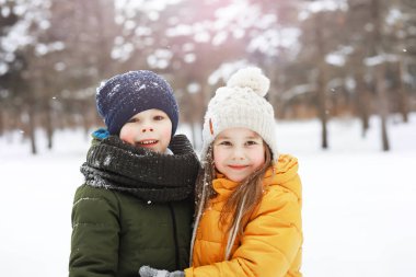 Mutlu bir aile kışın dışarıda karda oynar ve güler. Şehir parkı kış günü.