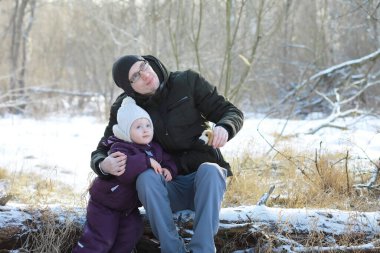 Mutlu bir aile kışın dışarıda karda oynar ve güler. Şehir parkı kış günü.